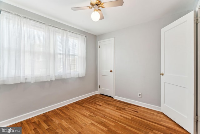 empty room featuring a ceiling fan, baseboards, and wood finished floors