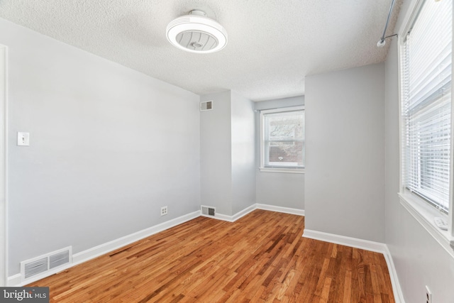 empty room with light wood finished floors, baseboards, and visible vents