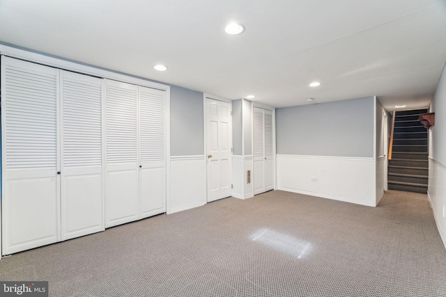 finished basement featuring a wainscoted wall, stairway, carpet flooring, and recessed lighting