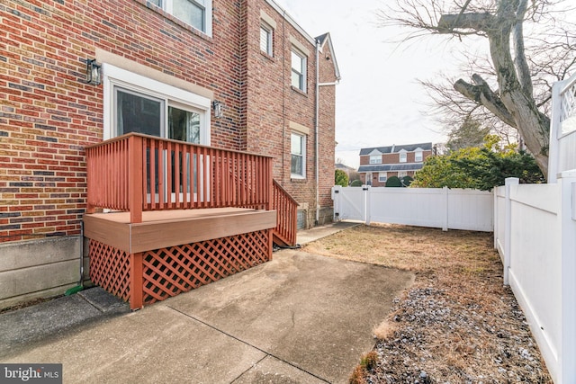 view of side of home featuring a patio area, a fenced backyard, brick siding, and a wooden deck