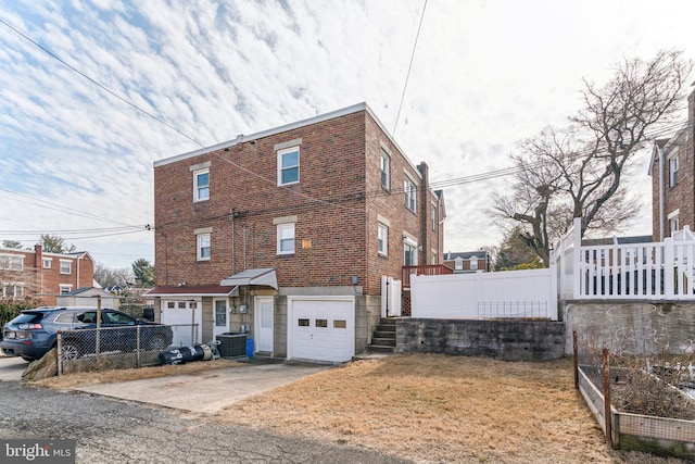 view of front of house featuring a garage, fence, cooling unit, and brick siding