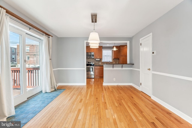 interior space featuring baseboards and light wood finished floors