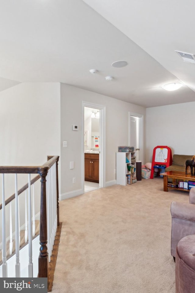 living area with baseboards, an upstairs landing, visible vents, and light colored carpet