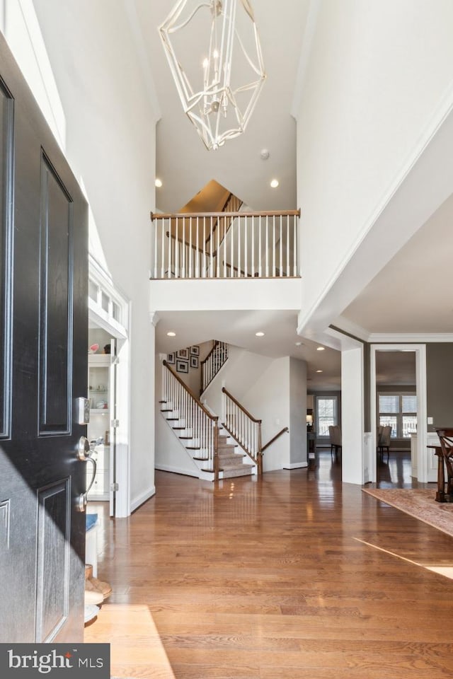 entryway featuring stairs, a high ceiling, wood finished floors, and a chandelier