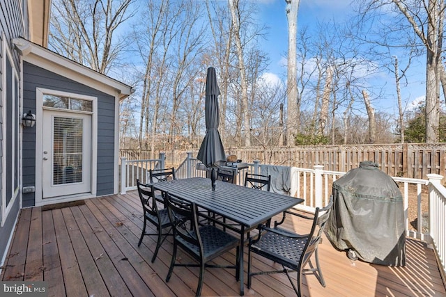 wooden terrace with outdoor dining space, area for grilling, and fence