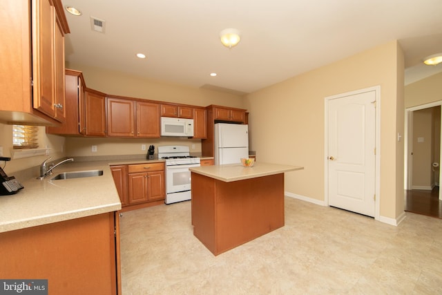 kitchen featuring white appliances, visible vents, a center island, light countertops, and a sink