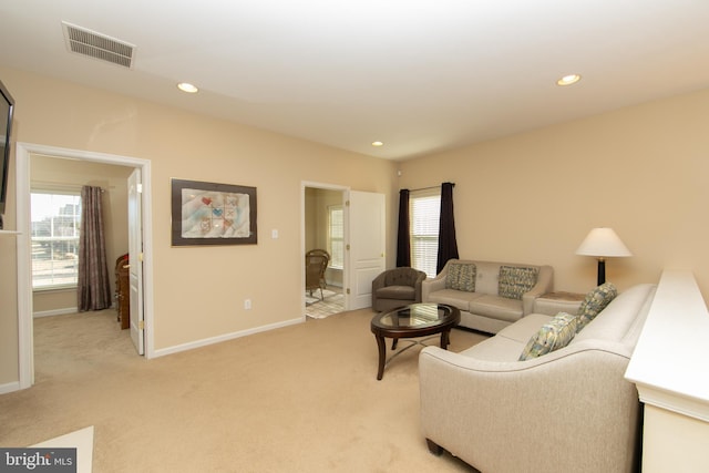 living area featuring baseboards, recessed lighting, visible vents, and light colored carpet