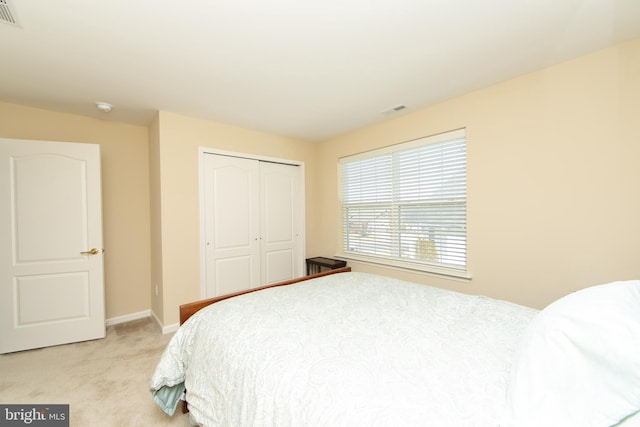 bedroom featuring light carpet, baseboards, visible vents, and a closet