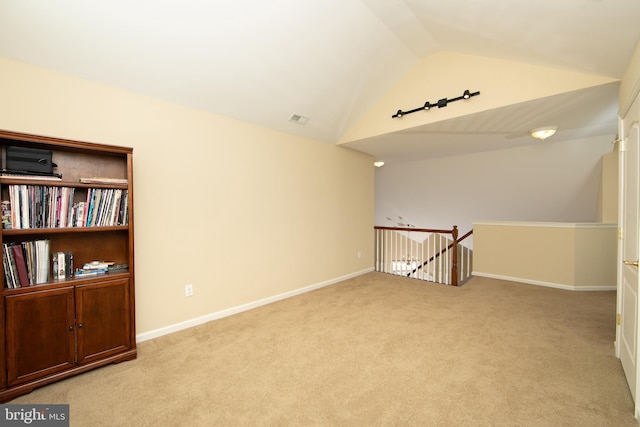 spare room with carpet, visible vents, vaulted ceiling, and baseboards