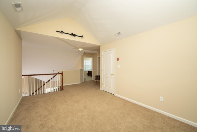 carpeted spare room featuring visible vents, vaulted ceiling, and baseboards