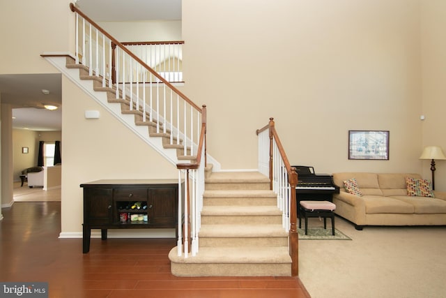 stairs featuring baseboards, a high ceiling, and wood finished floors