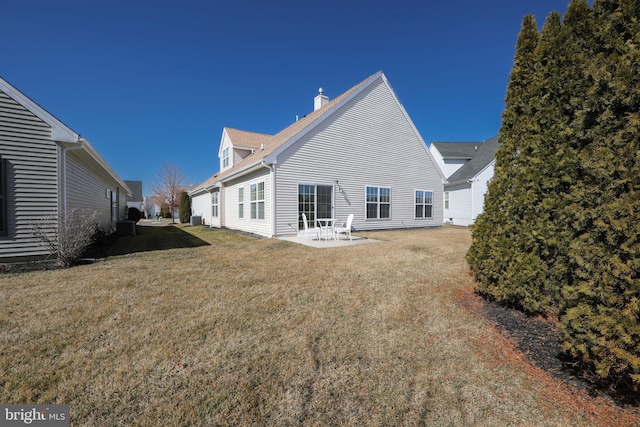 back of property with a yard, a chimney, and a patio area