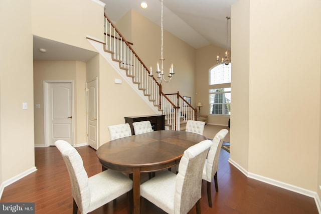 dining space featuring a chandelier, high vaulted ceiling, dark wood-style flooring, baseboards, and stairs