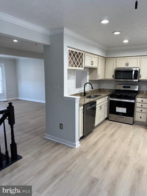 kitchen featuring stainless steel appliances, a sink, baseboards, light wood-type flooring, and crown molding