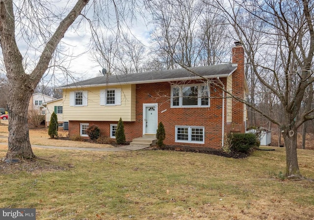 raised ranch featuring brick siding, a chimney, and a front lawn