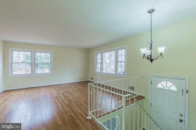 entryway featuring baseboards, visible vents, a chandelier, and wood finished floors