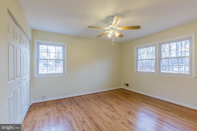 unfurnished bedroom featuring a closet, visible vents, light wood-style flooring, ceiling fan, and baseboards