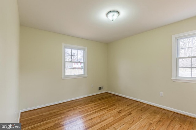 spare room with light wood-style flooring, visible vents, and baseboards