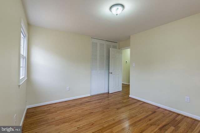 unfurnished bedroom featuring light wood-type flooring, baseboards, and a closet