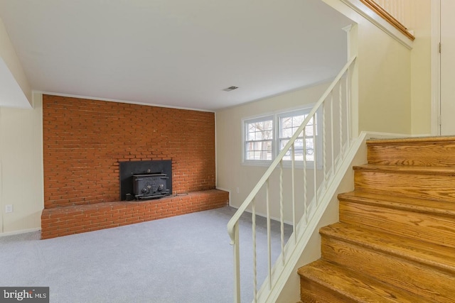 staircase with a wood stove, carpet, visible vents, and baseboards