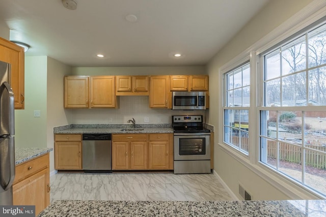 kitchen with visible vents, light stone countertops, marble finish floor, stainless steel appliances, and a sink