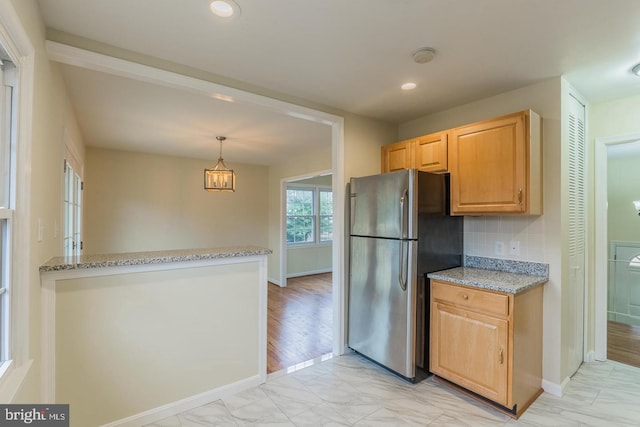 kitchen featuring light stone countertops, marble finish floor, recessed lighting, and freestanding refrigerator