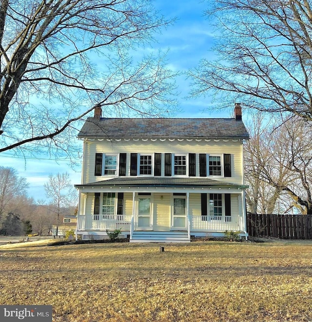 view of front facade featuring a chimney, fence, a porch, and a front yard