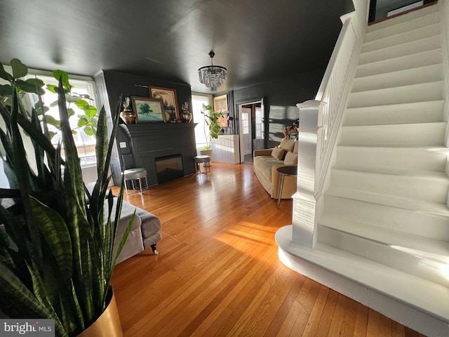 living room with a chandelier, wood-type flooring, a fireplace, and stairs