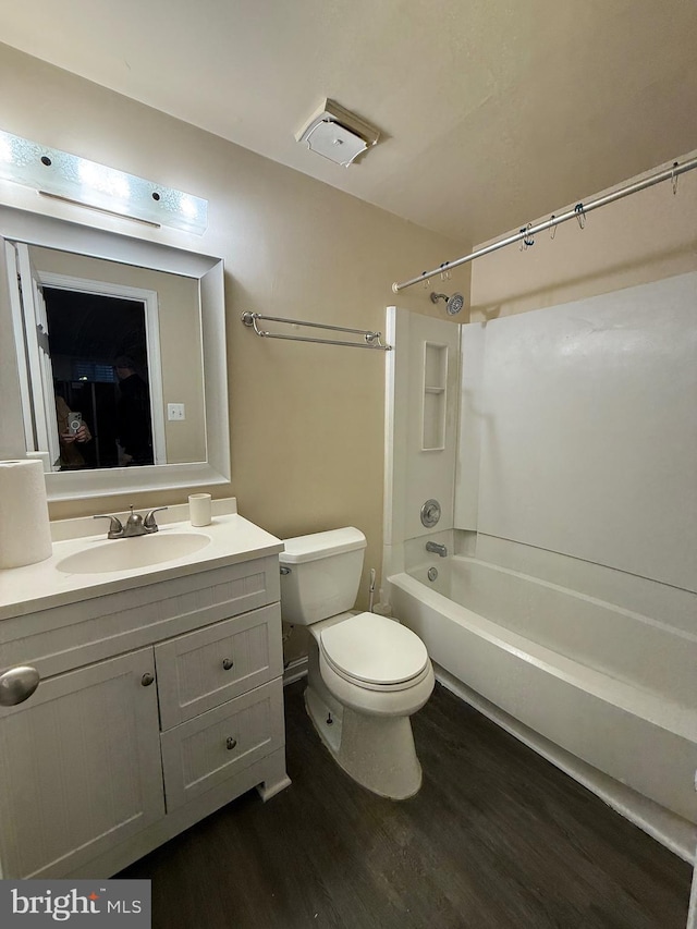 full bath with washtub / shower combination, vanity, wood finished floors, and toilet