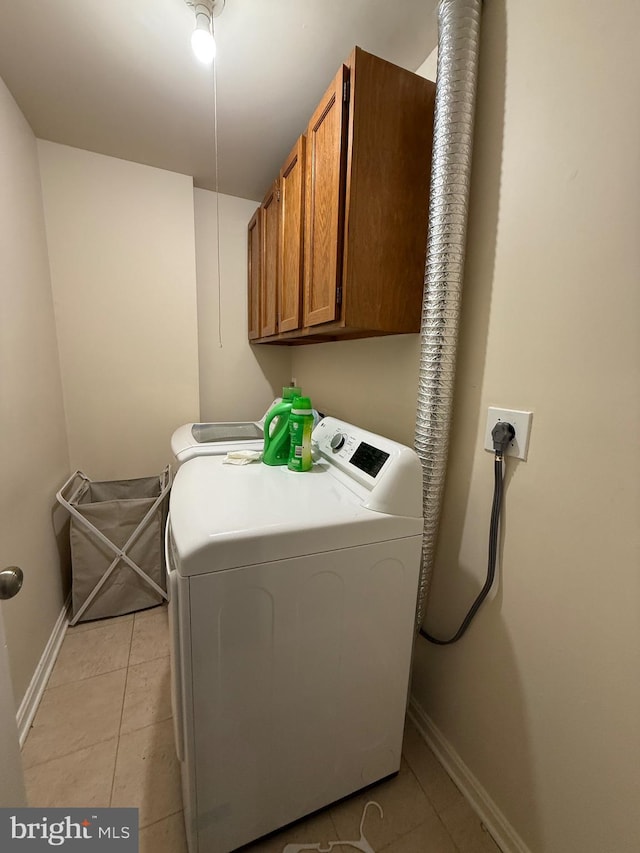 laundry area with cabinet space, light tile patterned floors, baseboards, and washer and clothes dryer