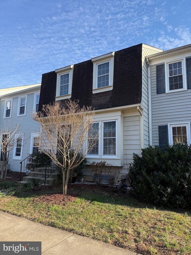 view of front of house with a shingled roof and mansard roof