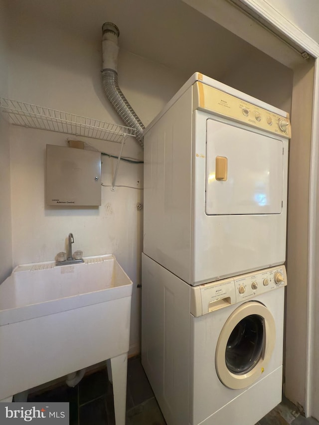 washroom with a sink and stacked washer / drying machine