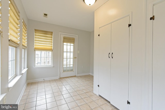 unfurnished bedroom with a closet, visible vents, baseboards, and light tile patterned flooring