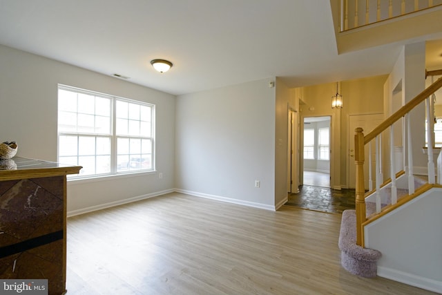 interior space featuring wood finished floors, visible vents, baseboards, and stairs