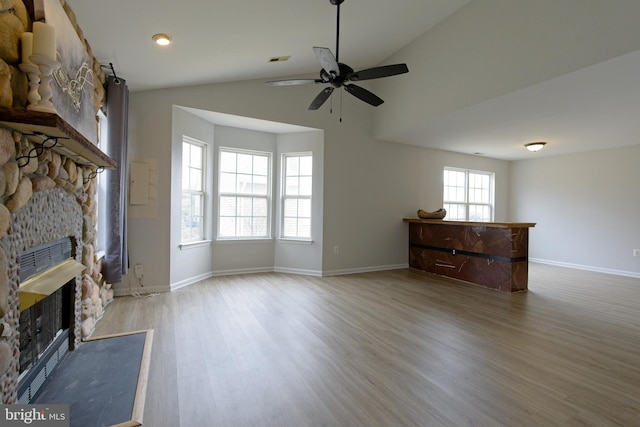 unfurnished living room featuring baseboards, visible vents, wood finished floors, vaulted ceiling, and a fireplace