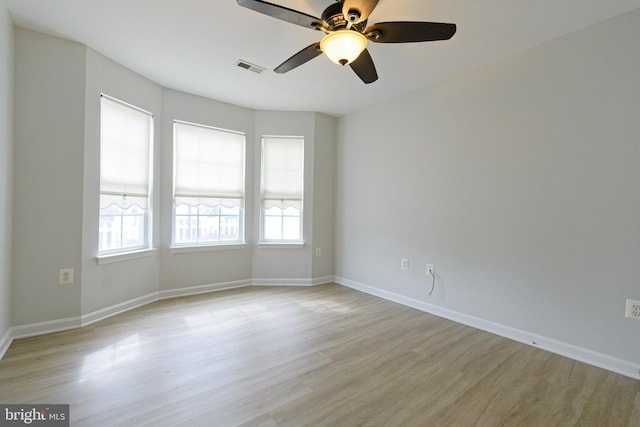 empty room with light wood-style floors, visible vents, baseboards, and a ceiling fan