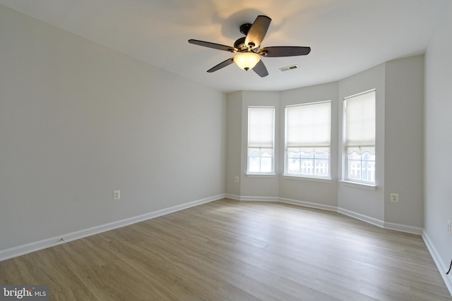 empty room featuring visible vents, ceiling fan, light wood-style flooring, and baseboards