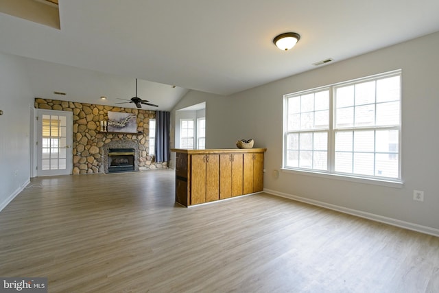 unfurnished living room featuring light wood finished floors, baseboards, ceiling fan, vaulted ceiling, and a fireplace