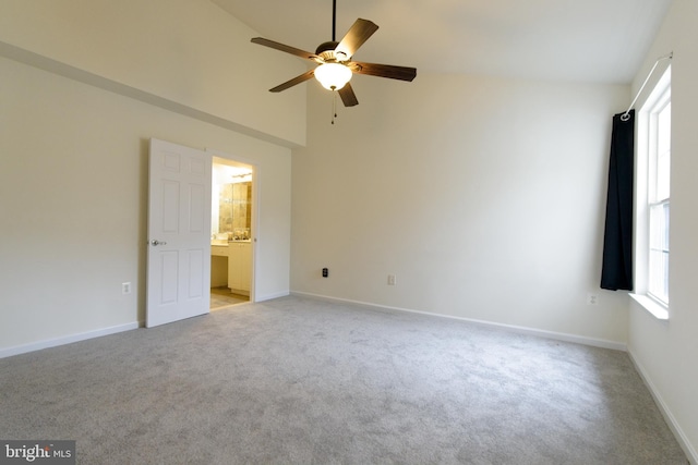 unfurnished bedroom featuring light carpet, baseboards, a ceiling fan, ensuite bathroom, and high vaulted ceiling