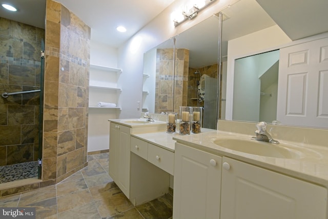 full bath featuring stone finish floor, tiled shower, a sink, and double vanity