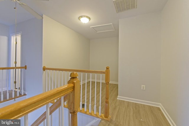 hall with attic access, baseboards, visible vents, wood finished floors, and an upstairs landing