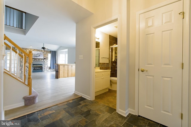 hall featuring stone tile flooring, vaulted ceiling, stairway, and baseboards