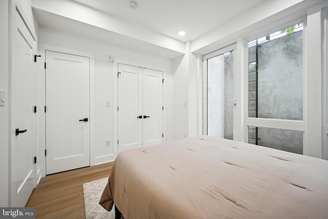 bedroom featuring recessed lighting, wood finished floors, and two closets