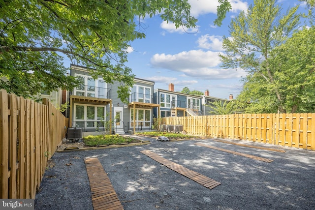 back of house featuring uncovered parking, fence private yard, and a balcony