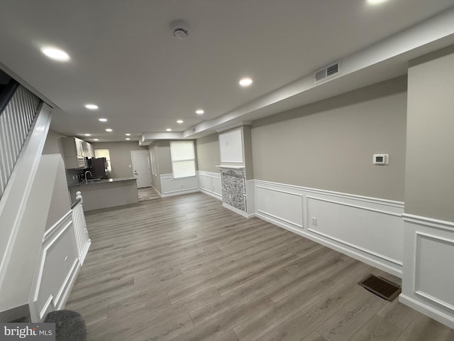 unfurnished living room featuring a sink, visible vents, wood finished floors, and recessed lighting