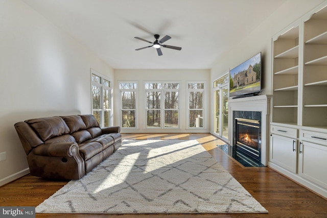 living room with dark wood finished floors, baseboards, ceiling fan, and a premium fireplace