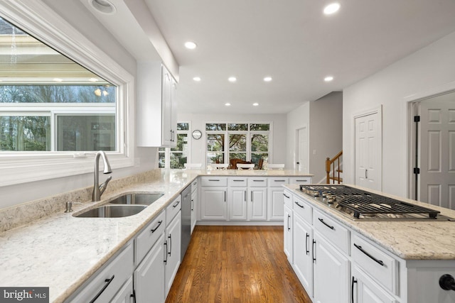 kitchen featuring white cabinets, appliances with stainless steel finishes, wood finished floors, and a sink