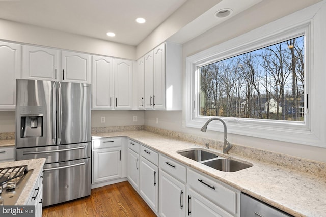 kitchen featuring wood finished floors, recessed lighting, a sink, stainless steel appliances, and white cabinets