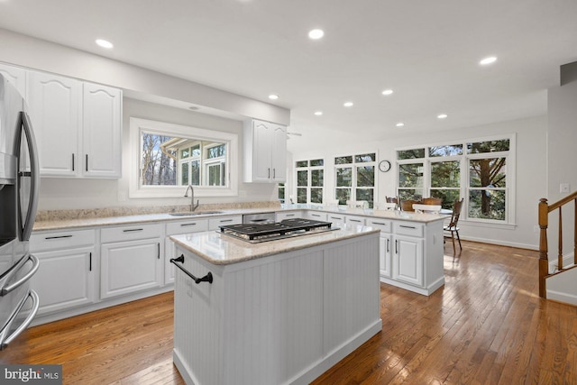 kitchen with a sink, stainless steel appliances, a kitchen island, and light wood-style flooring