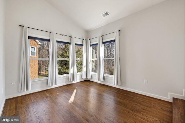 spare room with visible vents, baseboards, wood finished floors, and vaulted ceiling